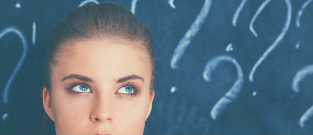 woman in front of chalkboard with question marks