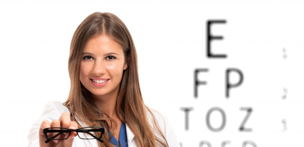 doctor holding glasses in front of blurry eye chart