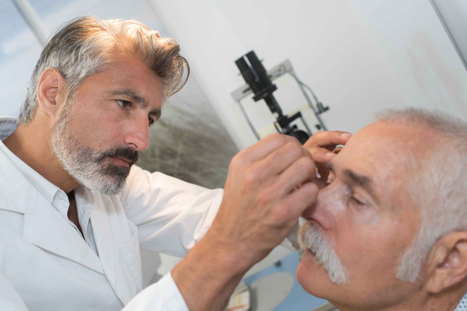 doctor putting eyedrops into patient's eyes