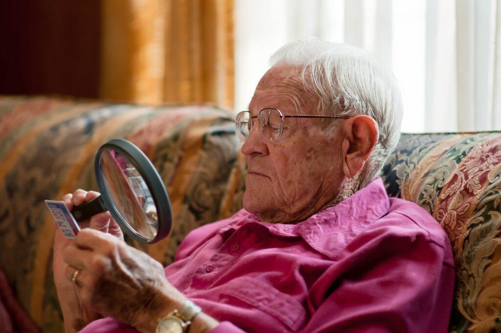 elderly man looking at object with magnifier