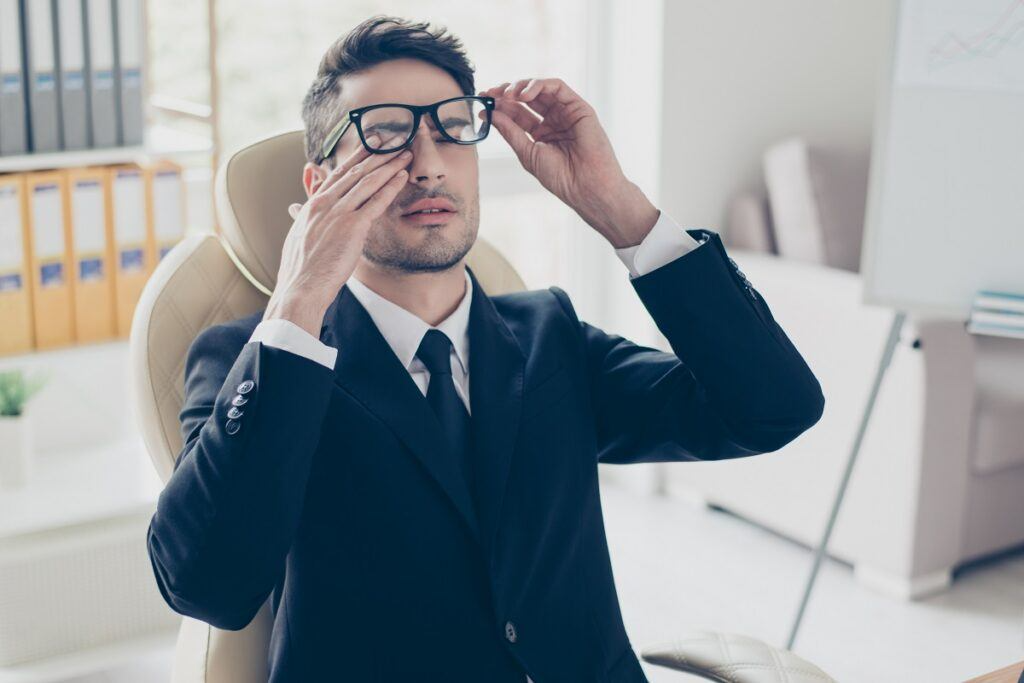 tired sleepy employee touching eyes and holding glasses