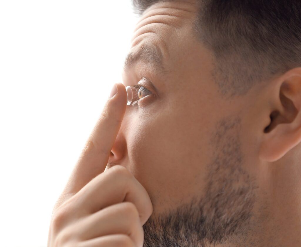 young man putting contact lens in his eye