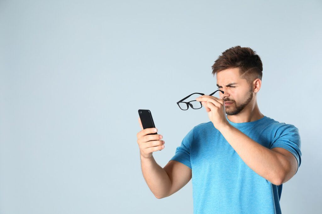 young man with vision problems using smartphone