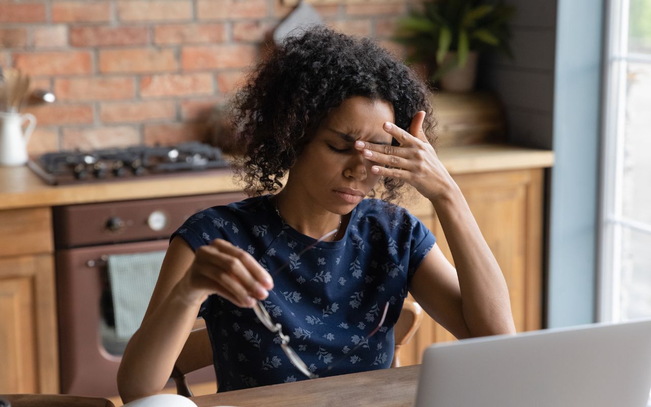 DLV woman is taking off her glasses due to a headache. 