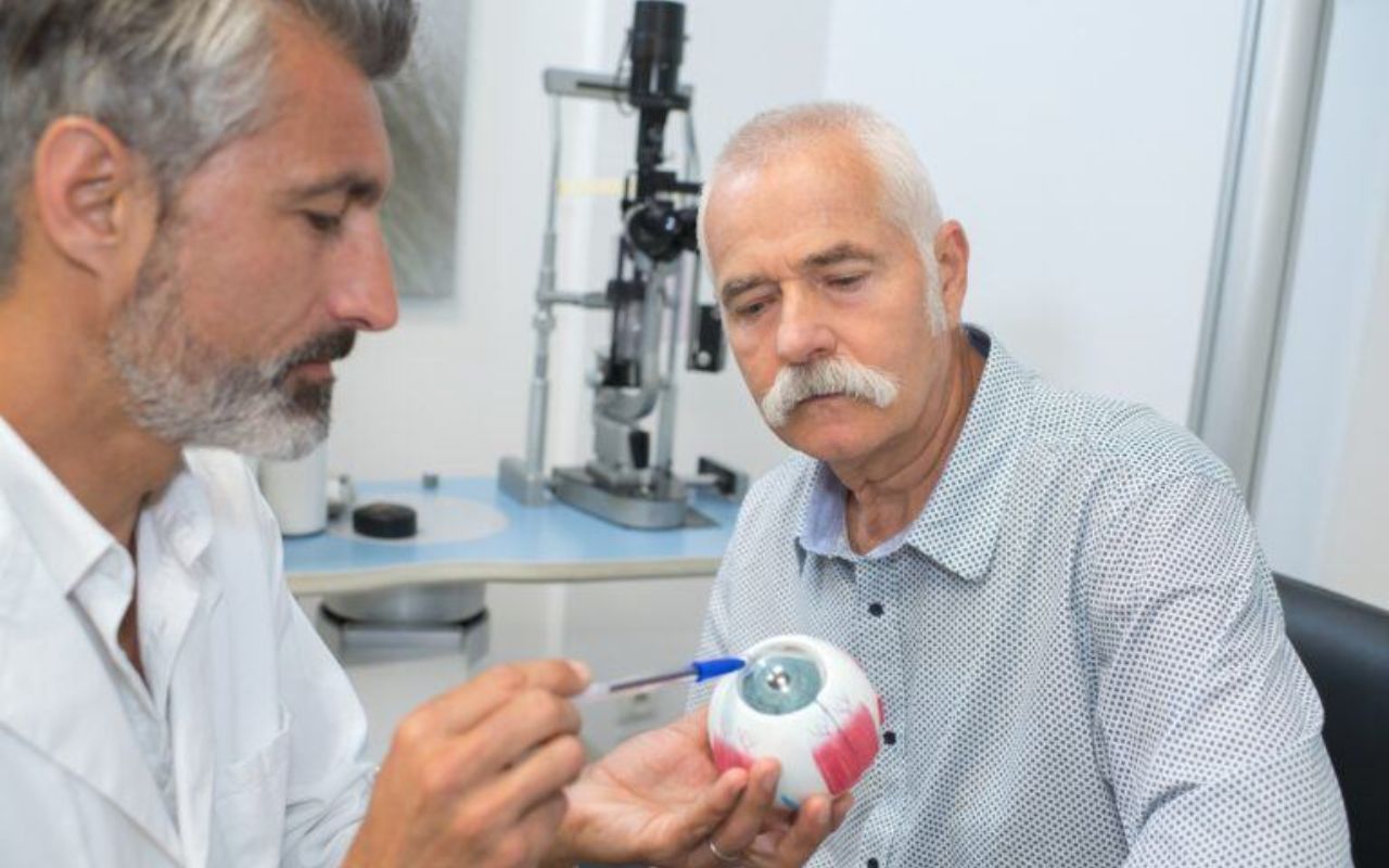 An optometrist showing eye model to senior patient
