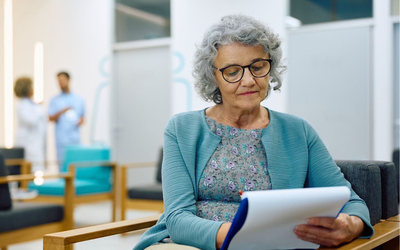 A senior woman is filling out paperwork before an eye exam.