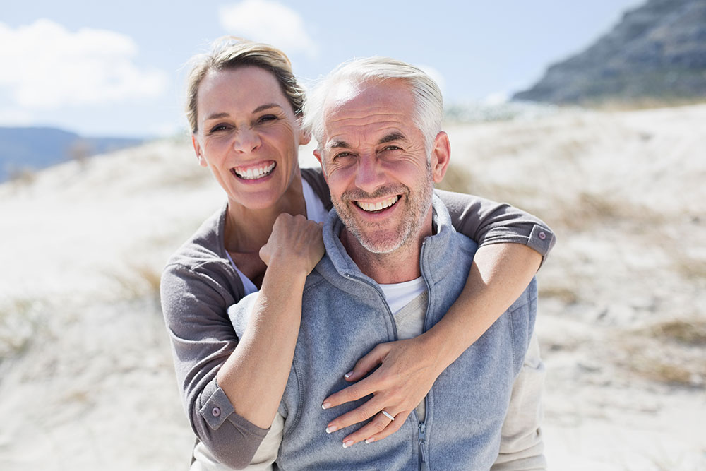 Joyful senior couple embracing and smiling on a sunny beach